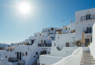 Arquitetura grega mediterrânea com casas brancas, luz intensa e vida ao ar livre