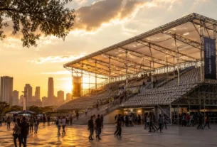 Estádio modular efêmero integrado ao skyline urbano ao entardecer