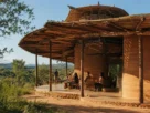 Edifício de arquitetura regenerativa e biomimética construído com terra e madeira local, integrado à vegetação nativa