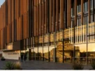 Fachada contemporânea com lâminas de brise-soleil projetando sombras sobre vidro ao entardecer